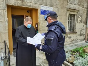 Policjant przekazuje ulotki księdzu