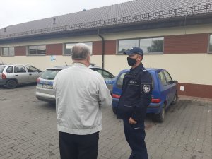 Policjant przed marketem rozmawia z mieszkańcem