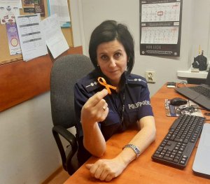 Policjantka trzyma w ręku pomarańczową wstążkę