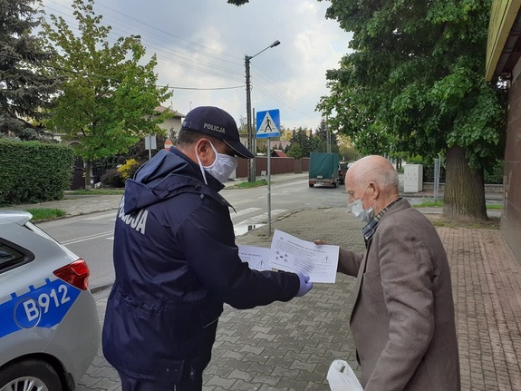 Policjant wręcza ulotki seniorowi