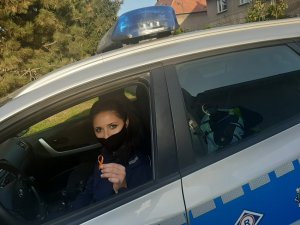 Policjantka w radiowozie trzyma w ręku pomarańczową wstążkę