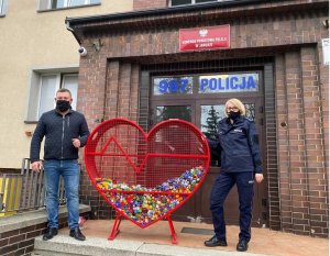 Policjantka i mężczyzna stoją przy sercu wypełnionym nakrętkami